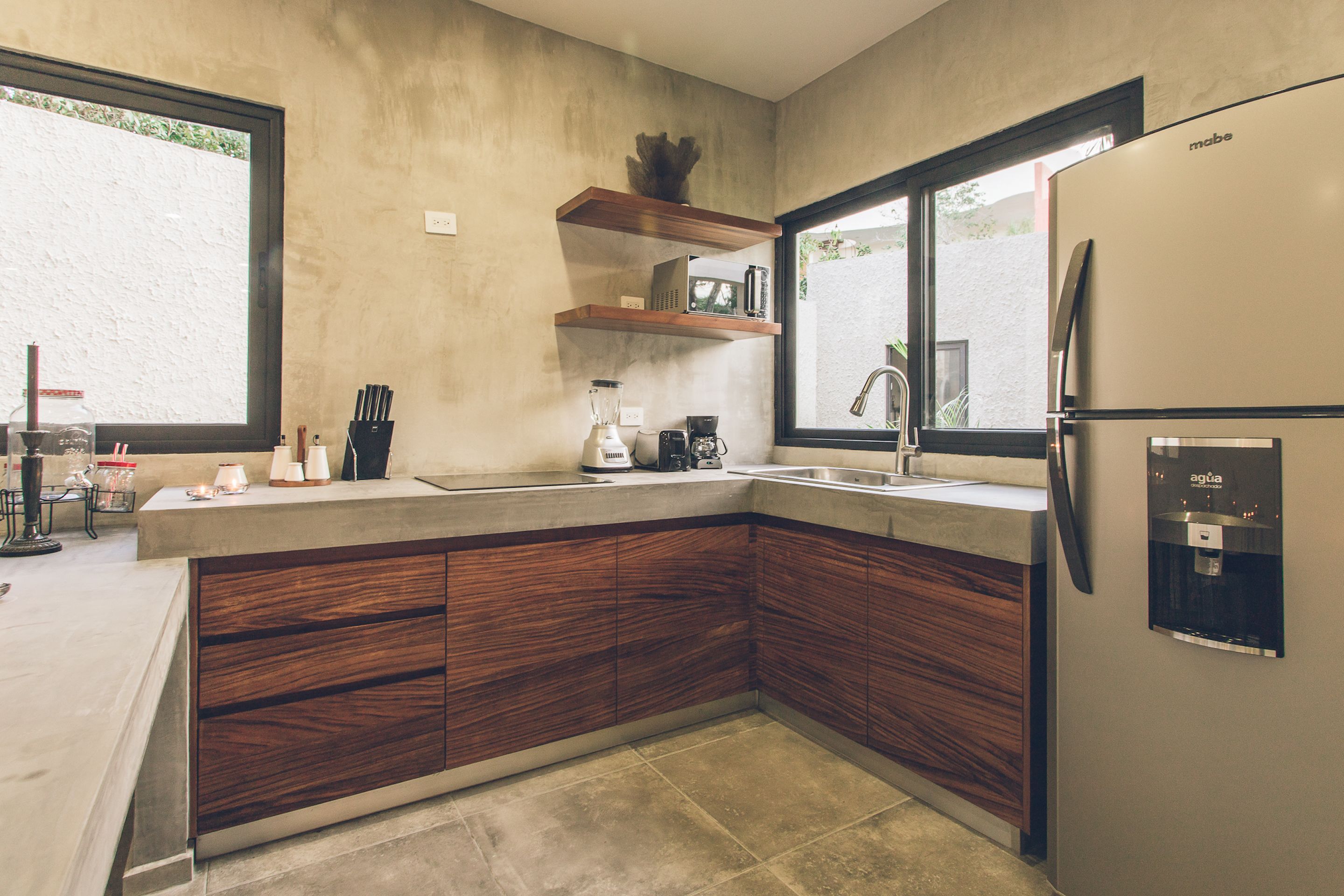 A modern kitchen with wooden cabinets, a built-in microwave, a coffee maker, and a water dispenser.