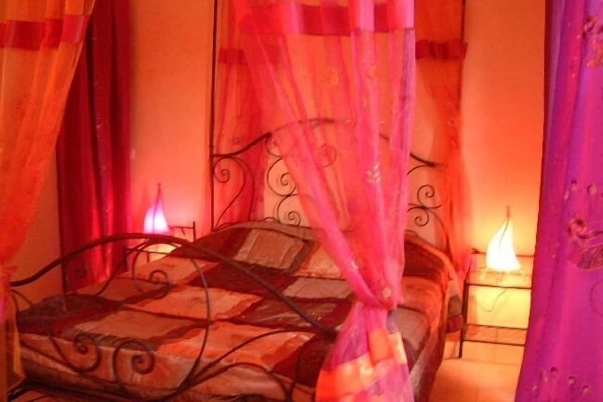 A bed with a canopy, a bedside table, and a wall with a decorative pattern.