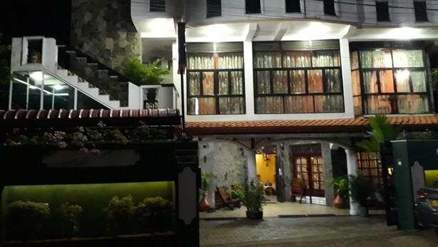 A two-story building with a stone facade, a tiled roof, and multiple windows with curtains. - Basilico Homestay (Kegalle)