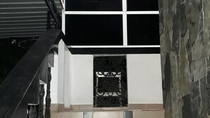 A staircase with a black railing leading to a landing with a fireplace. - Basilico Homestay (Kegalle)