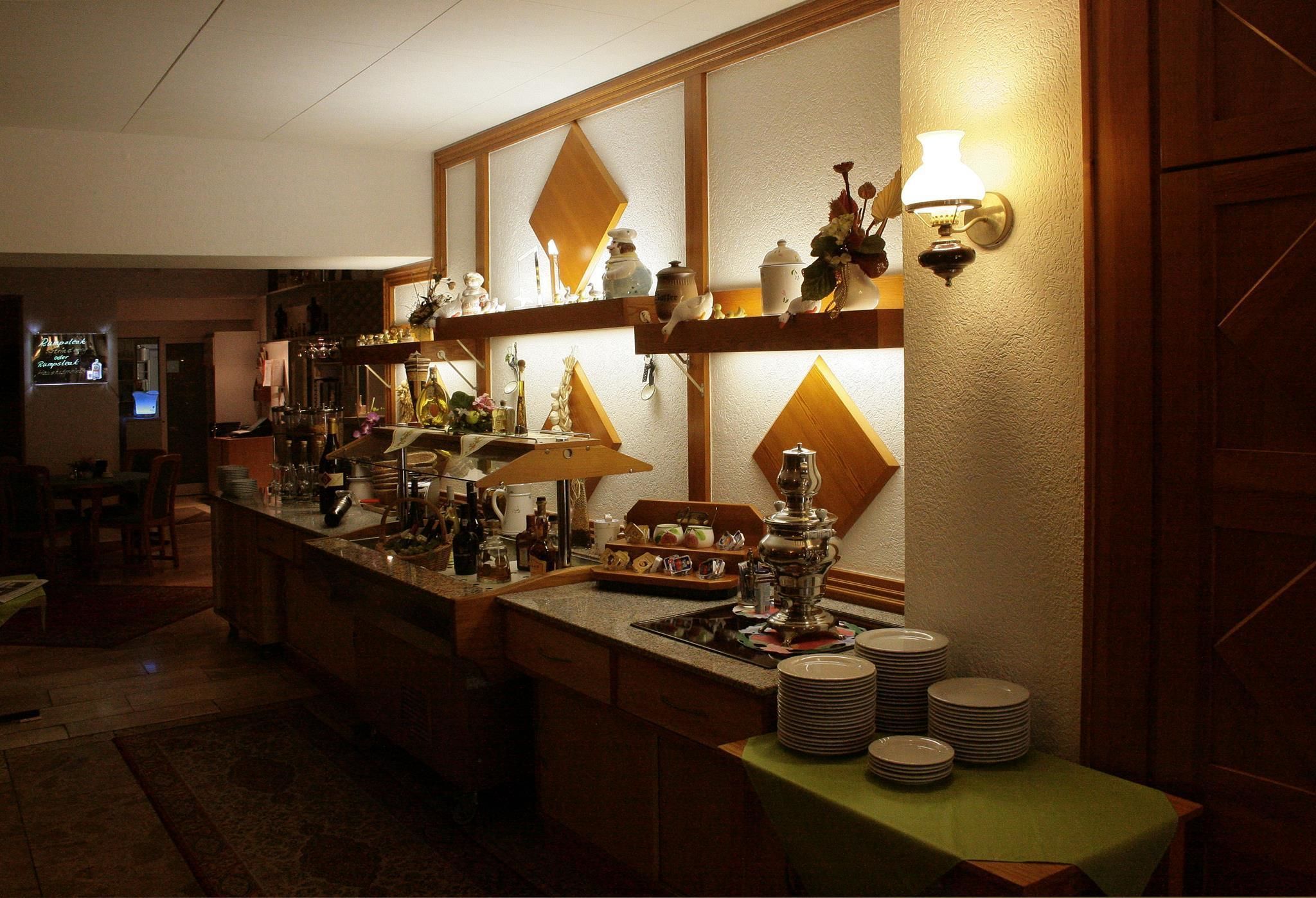 A bar area with a counter, shelves with various items, and a wall-mounted light fixture.