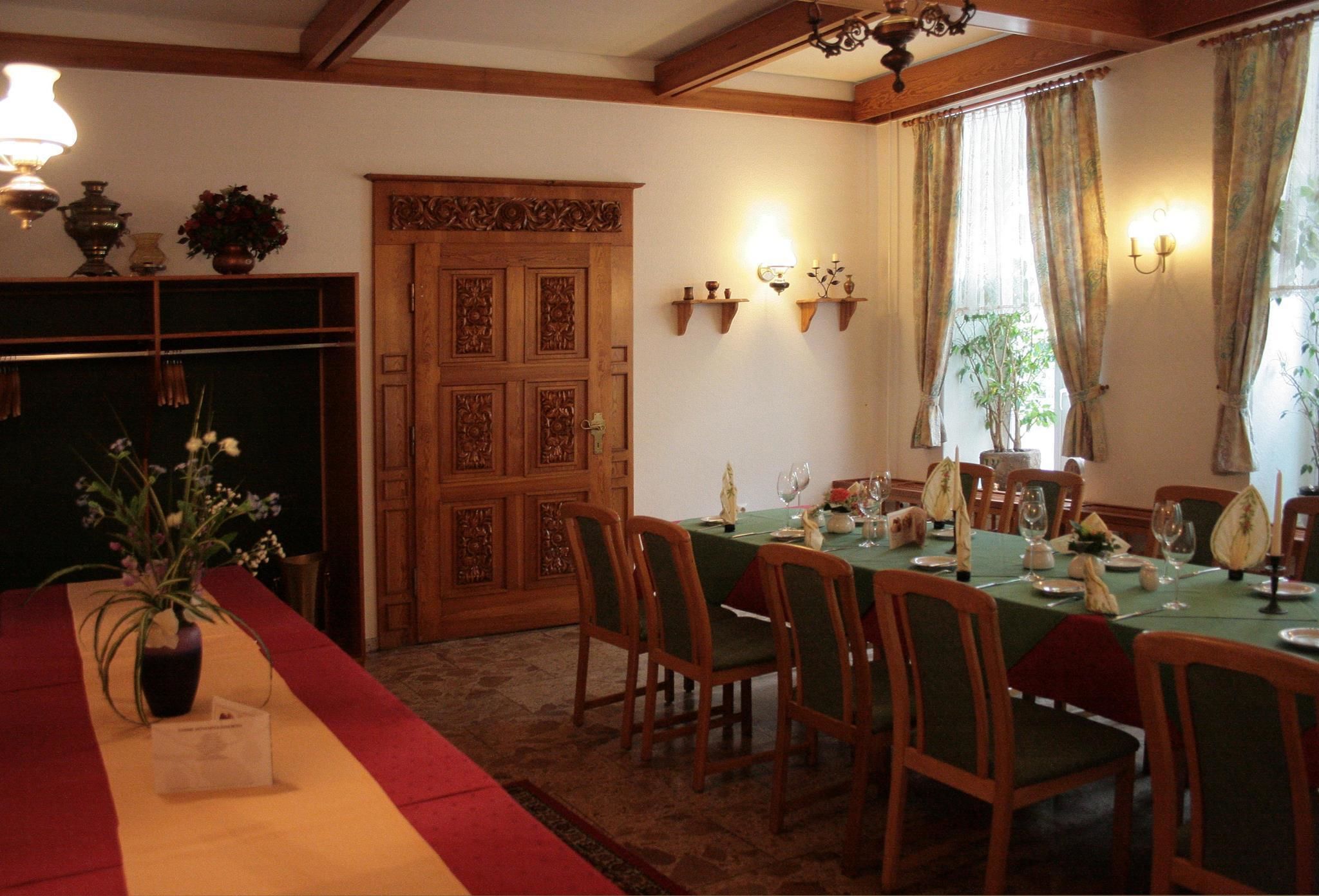 A dining room with a long table set for a meal, wooden chairs, and a decorative door.