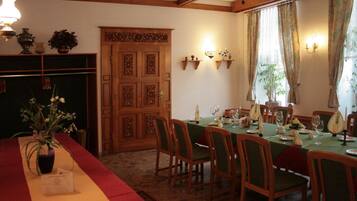 A dining room with a long table set for a meal, wooden chairs, and a decorative door.