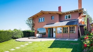 A two-story house with a large front porch, a chimney, and a well-maintained lawn. - La Barraca Suites (San Carlos de Bariloche)