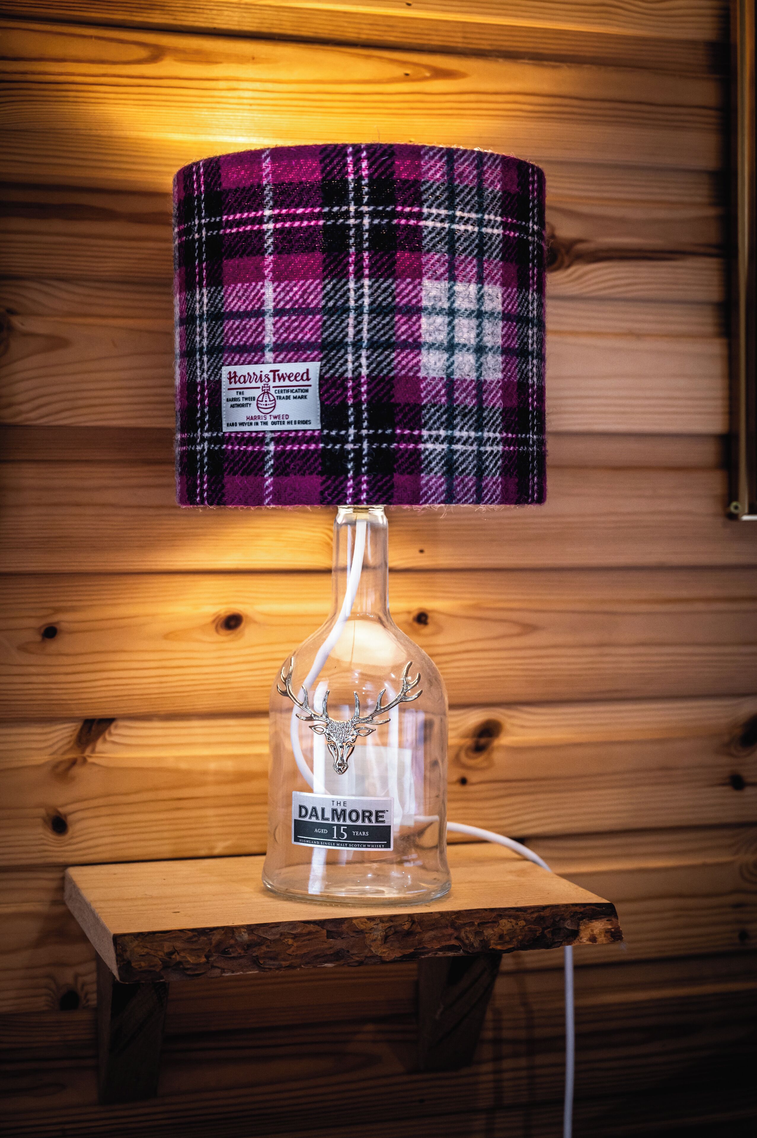 A lamp with a plaid lampshade on a wooden table.