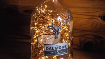 A bottle of Dalmore whisky with a deer head ornament and string lights inside.