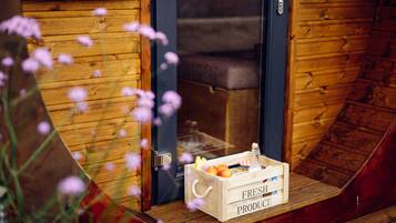 Una porta di legno con un cartello che recita "LEE NIP" e una cassa con l'etichetta "PRODOTTI FRESCHI" contenente frutta e una bottiglia sul portico.