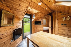 A wooden cabin interior with a fireplace, a television, and a dining table.