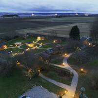 A rural property with a winding driveway, multiple buildings, and a large open field.