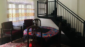Ein Essbereich mit einem runden Tisch, Stühlen und einer Treppe mit schwarzer Geländer.