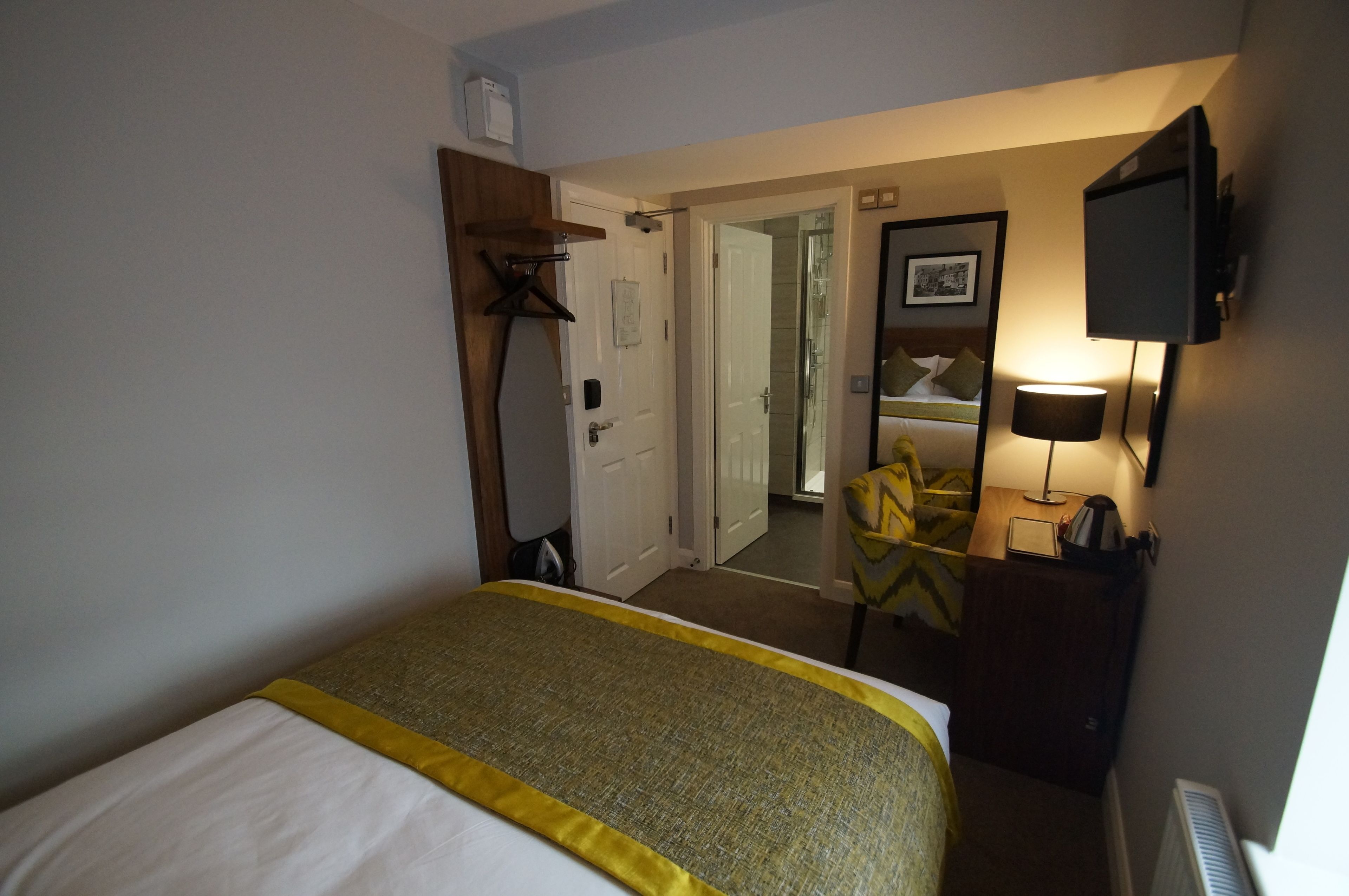 Hotelkamer met een bed, een bureau, een stoel, een televisie en een deur naar een andere kamer.