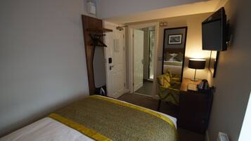 Hotelkamer met een bed, een bureau, een stoel, een televisie en een deur naar een andere kamer.
