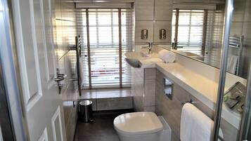 A modern bathroom with a toilet, sink, and glass shower enclosure.
