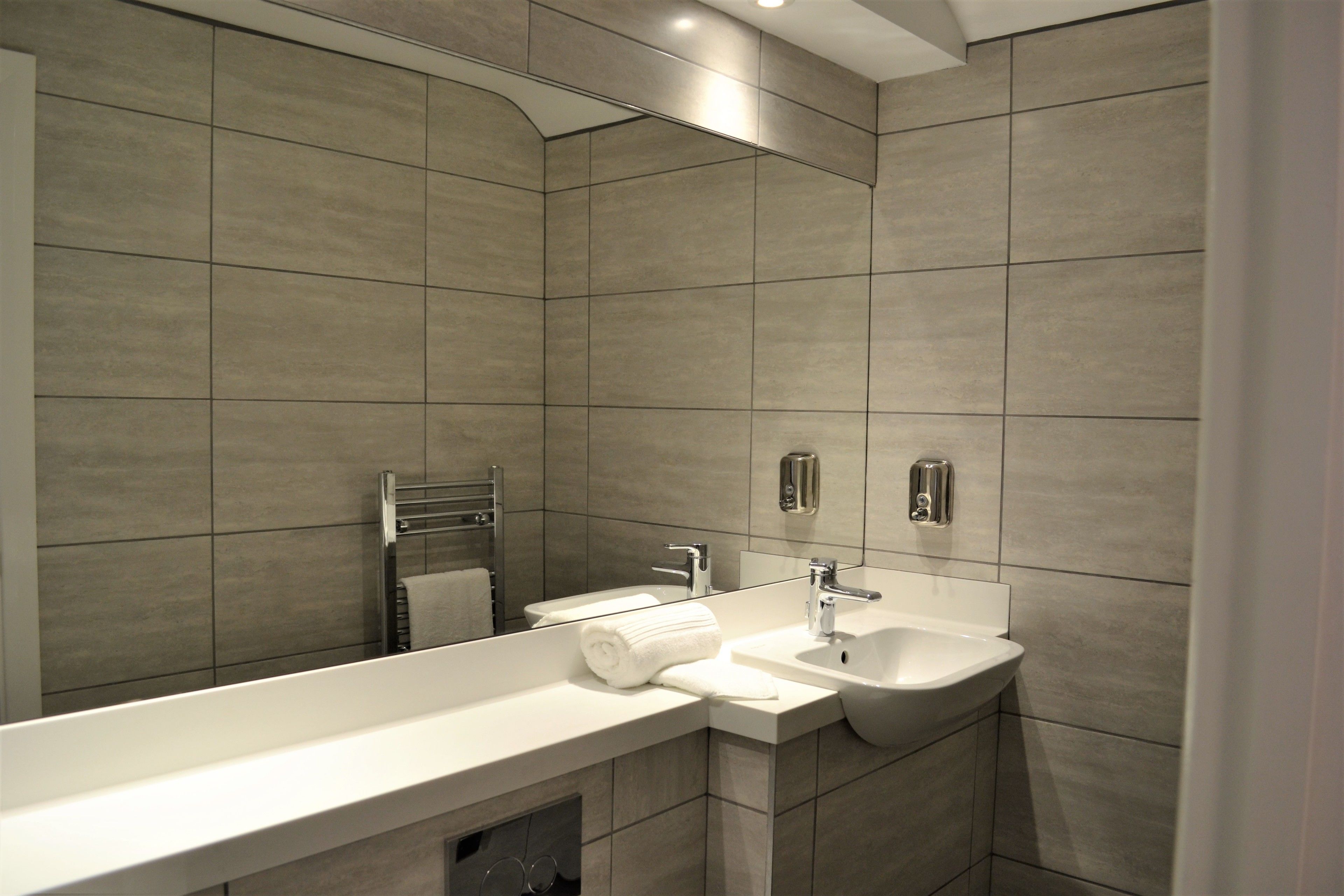 Une salle de bain moderne avec un grand miroir, un lavabo et un porte-serviettes.