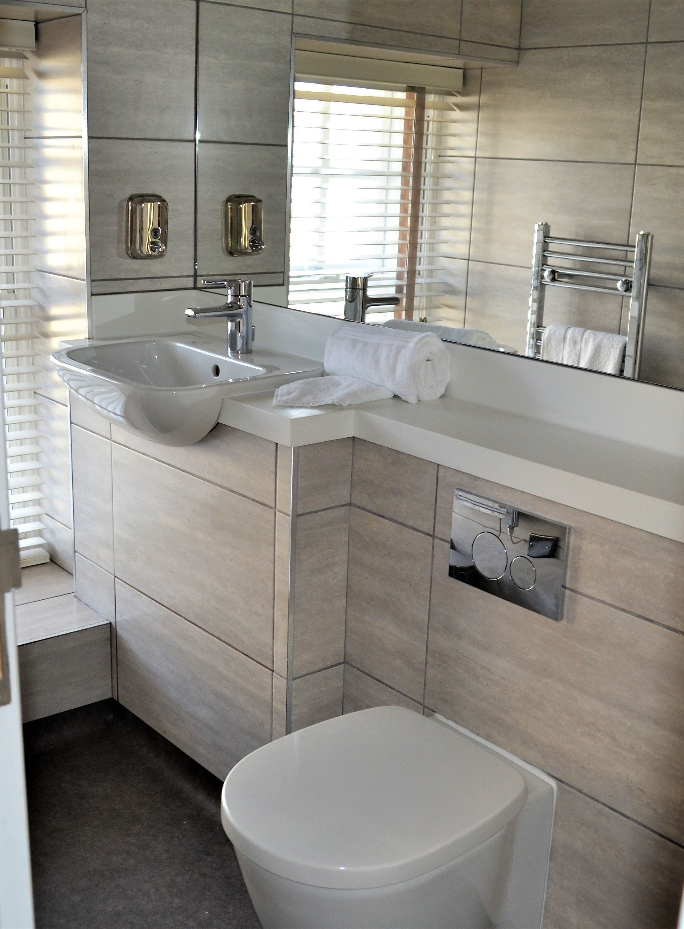 A modern bathroom with a large sink, a toilet, and a mirror.