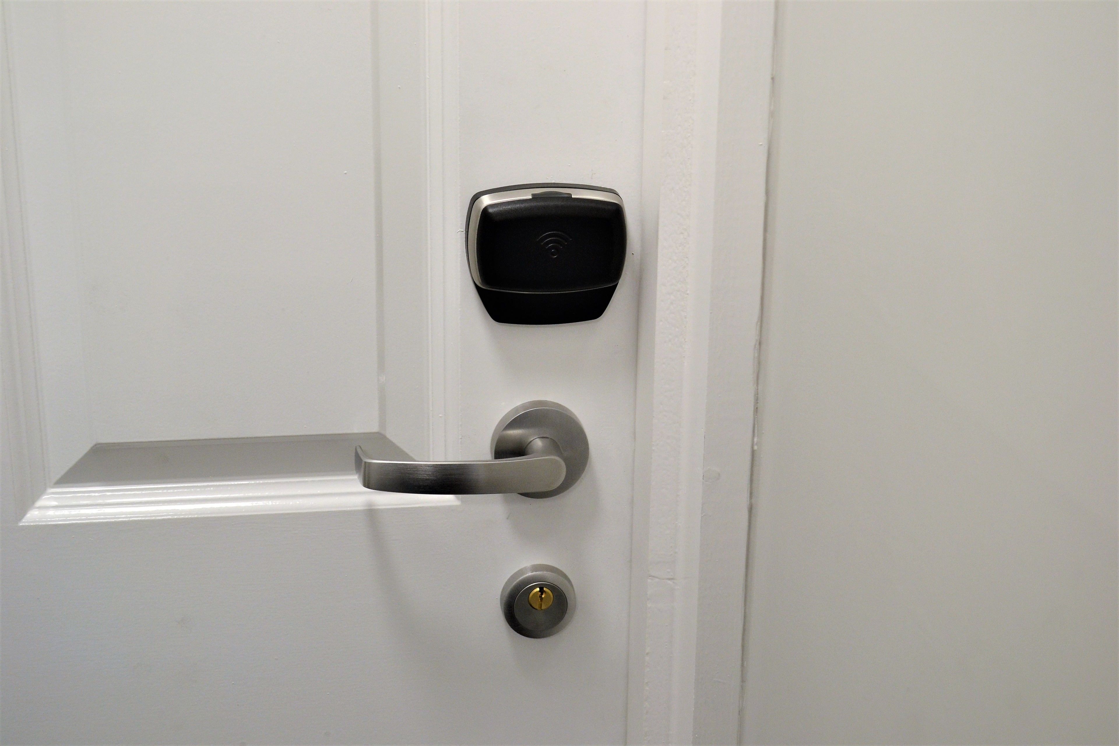 A modern door with a biometric fingerprint scanner and a traditional keyhole.
