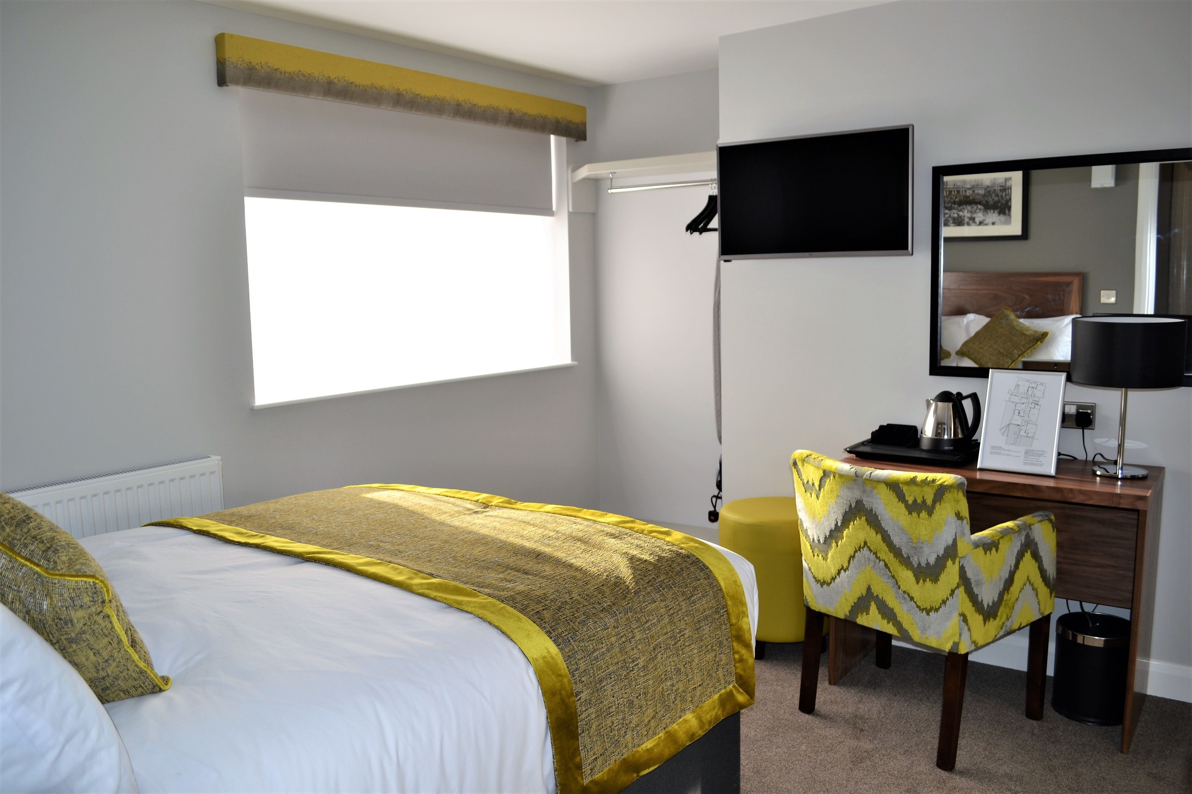 A hotel room with a bed, a desk, a chair, a television, and a window.