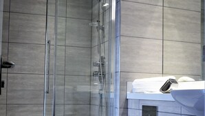 Une salle de bain moderne avec une douche à parois de verre, des toilettes blanches et un lavabo doté d’un porte-serviettes.