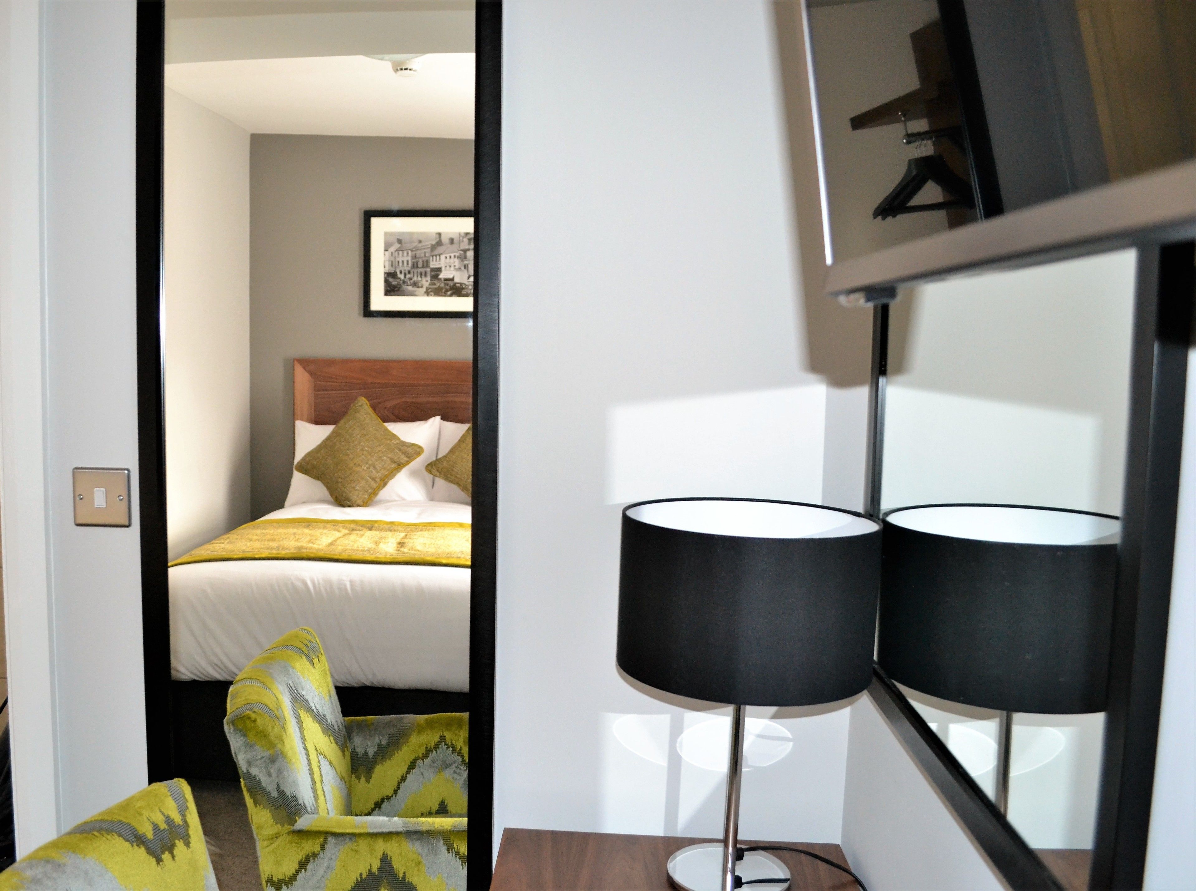 A hotel room with a bed, a chair, and a floor lamp.