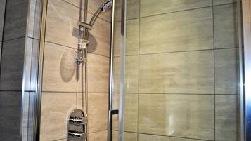 Eine Dusche mit Handbrause und Bedienfeld an der Wand.