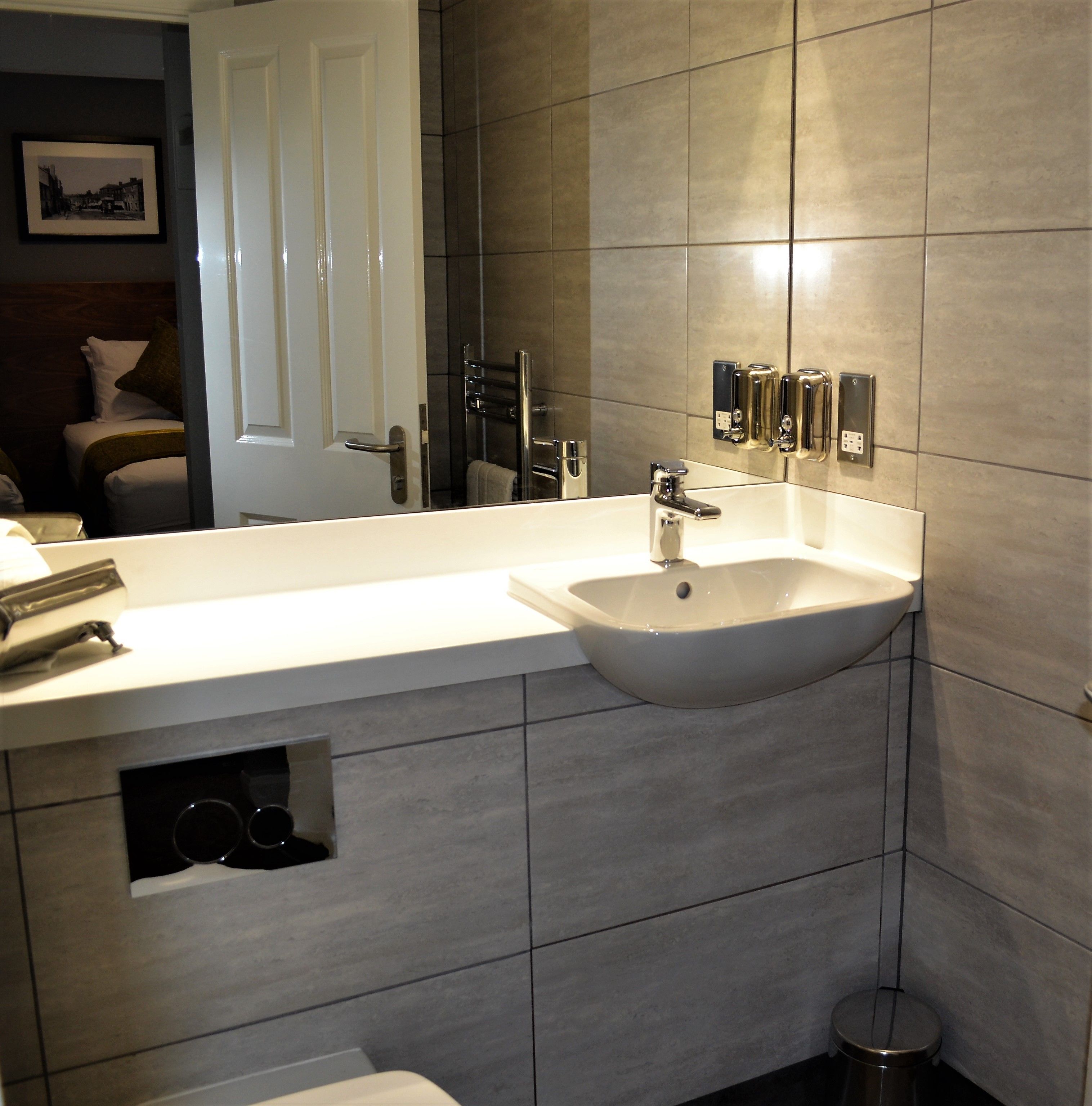 A modern bathroom with a white sink, a mirror, and a towel rack.
