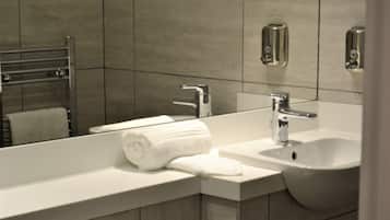 Un baño moderno con un lavamanos blanco, un espejo y un perchero para toallas.