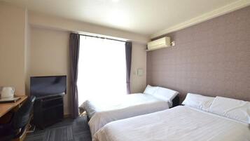 Une chambre d’hôtel avec deux lits, un bureau avec une télévision et un appareil de climatisation.