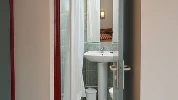 A bathroom with a shower, toilet, sink, and a mirror.