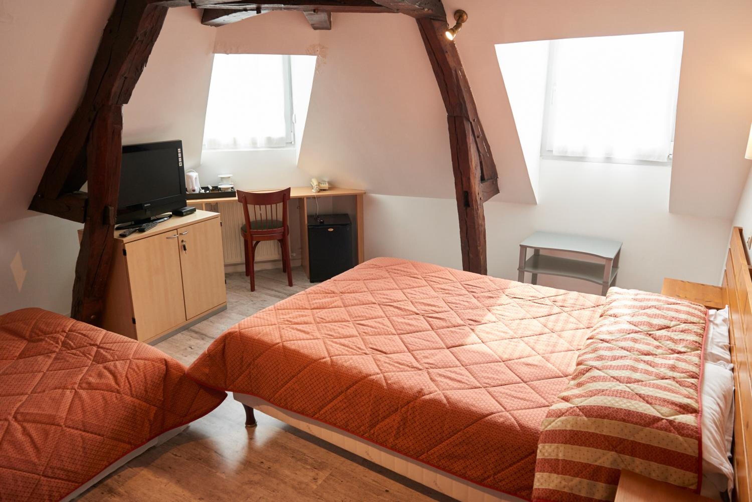 A bedroom with two beds, a desk, and a television.