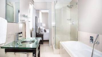 A modern bathroom with a glass sink, a walk-in shower, and a separate bathtub.
