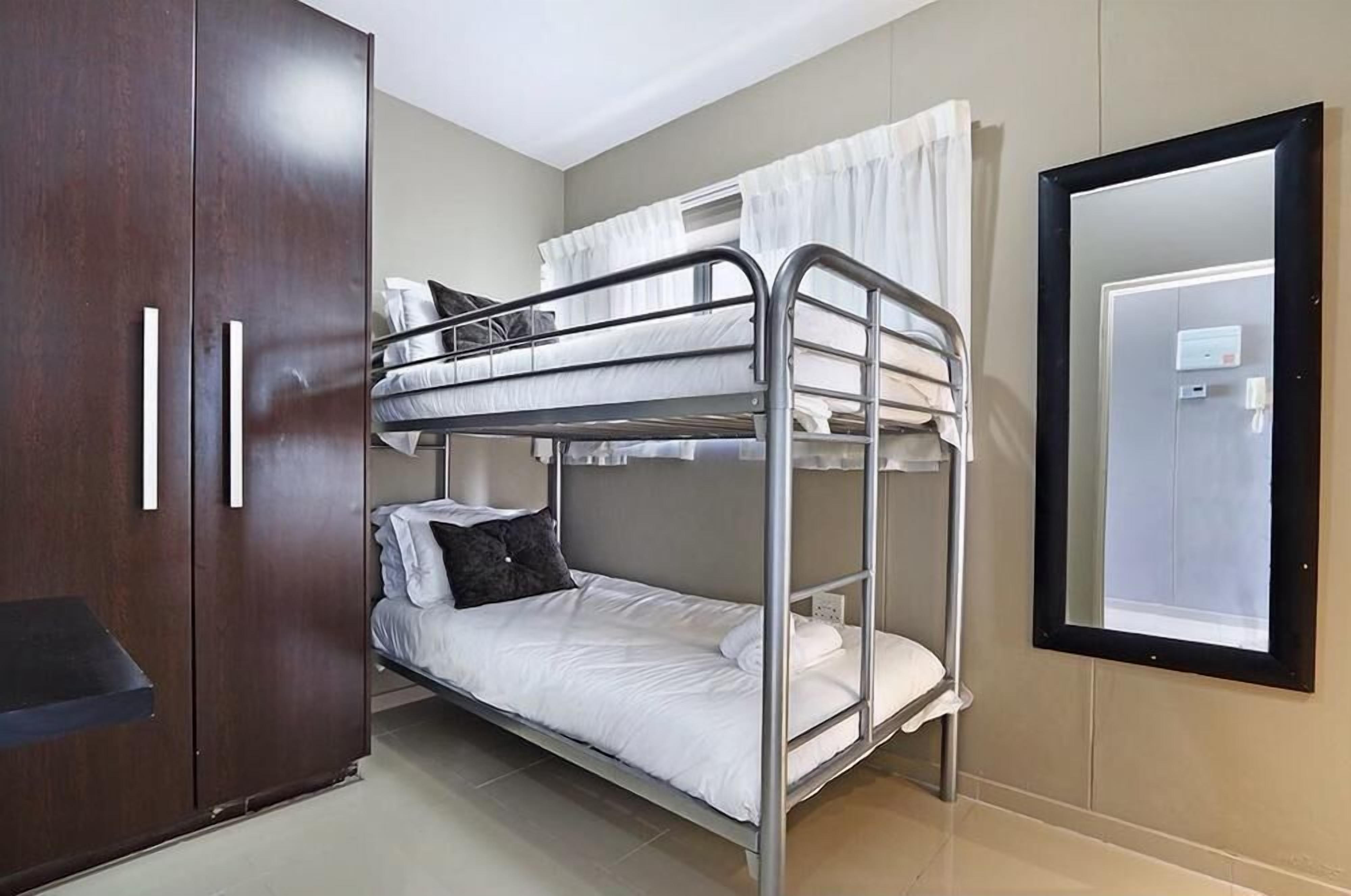 A bunk bed room with a wardrobe and a mirror.