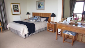 Une chambre à coucher bien rangée, avec un lit, des tables de chevet, une commode et un miroir.