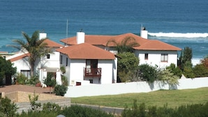 Une maison située sur la côte, avec un toit recouvert de tuiles rouges, des murs blancs et une vue sur l’océan.