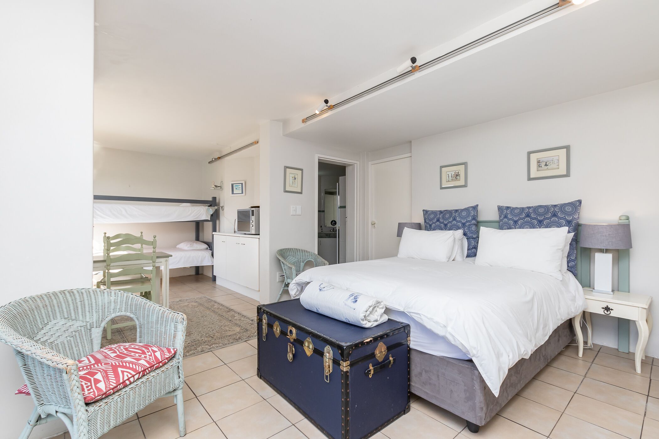 Ein Schlafzimmer mit Bett, Nachttisch, Kommode, Stuhl und Koffer.