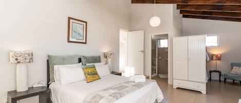 A bedroom with a bed, bedside tables, a wardrobe, and a door leading to another room.