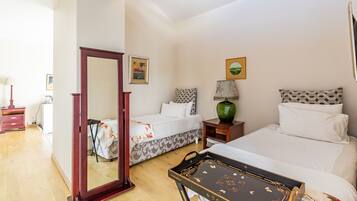 A bedroom with two beds, a mirror, a dresser, a lamp, and a framed picture on the wall.