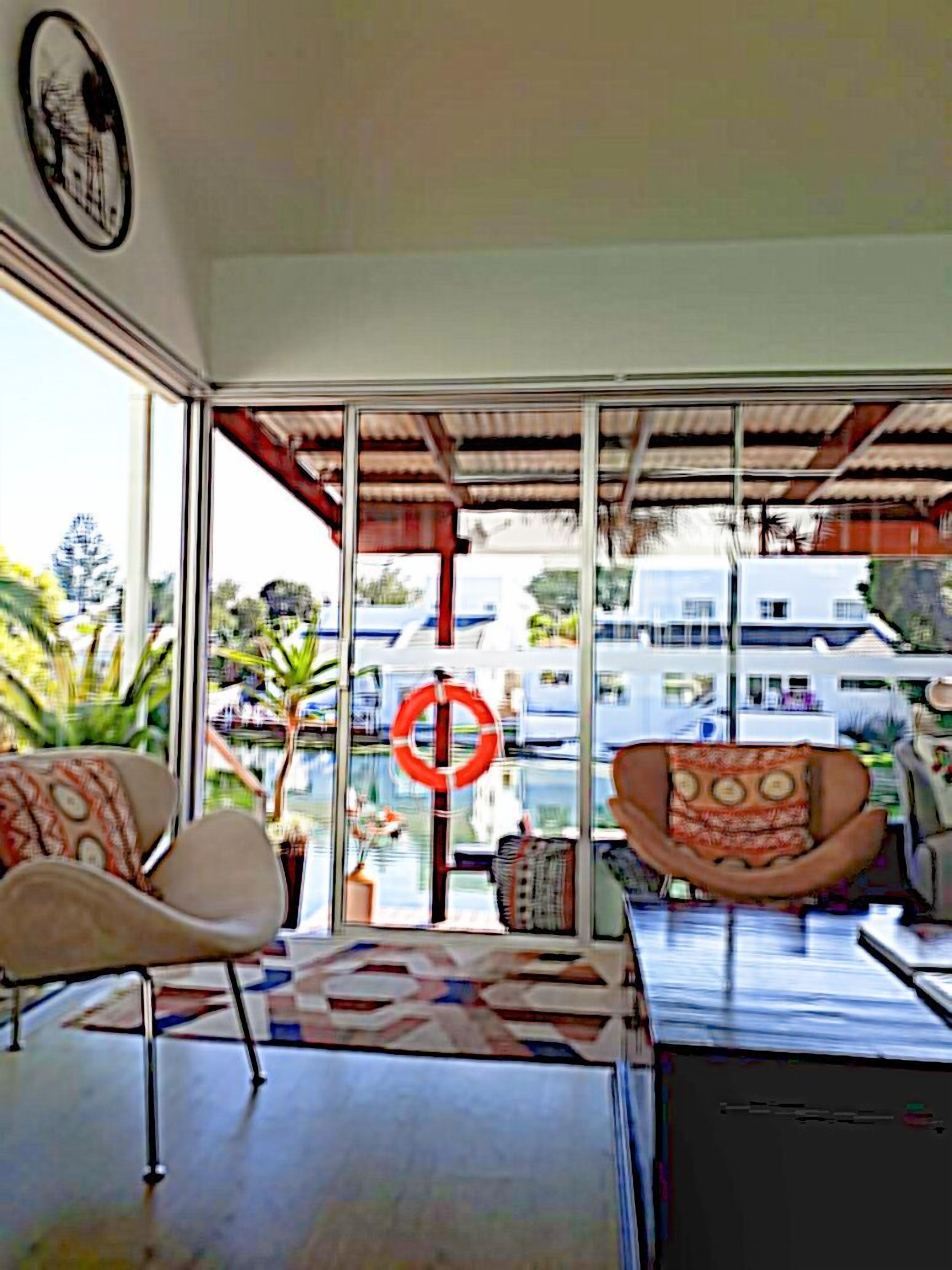 Una habitación con ventanas amplias, un sofá, una silla y una pequeña mesa.