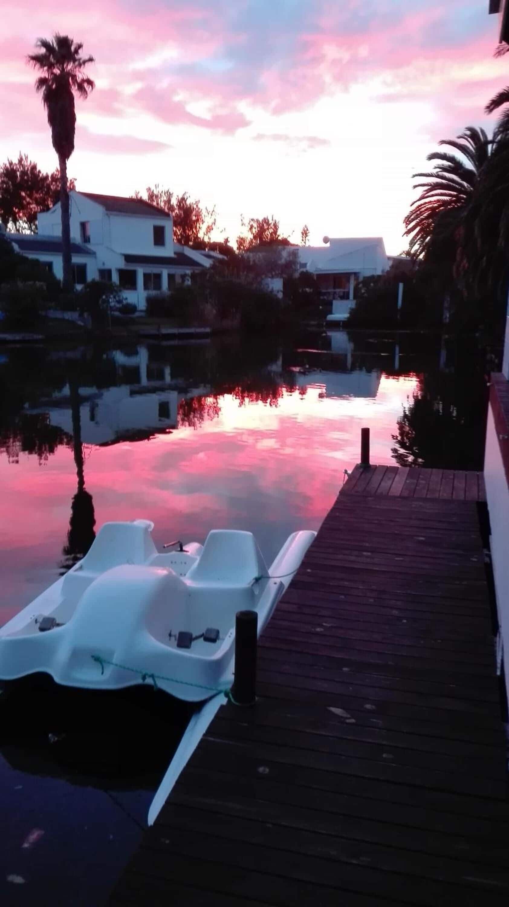 Rauhallinen rantapaikka, jossa on puinen laituri ja kaksi valkoista soutuvenettä.
