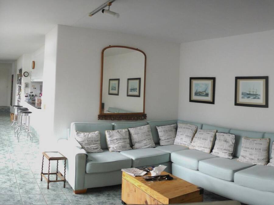 Una sala de estar con un sofá seccional azul claro, una mesa de centro de madera y un espejo grande sobre el sofá.