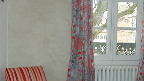 A room with a wooden chair, a radiator, and a window with curtains. - Le Clos de l'Abbaye (Cluny)