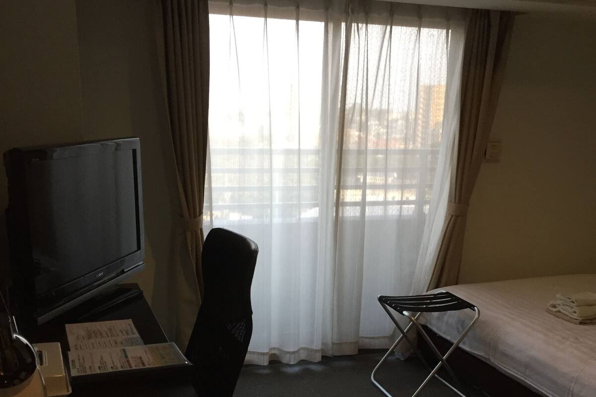 Een hotelkamer met een bureau, stoel, bed en een televisie.