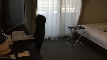 A hotel room with a desk, chair, bed, and a TV.