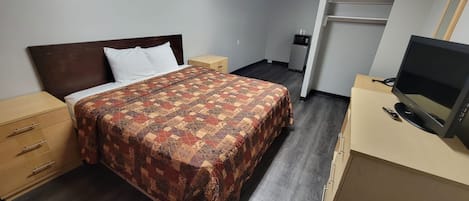 Una habitación de hotel con cama, televisión, escritorio y armario.