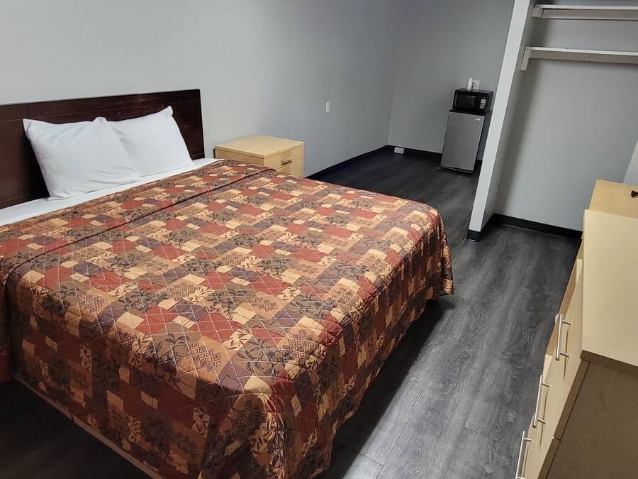 Ein Hotelzimmer mit Bett, Fernseher, Schreibtisch und Kleiderschrank.