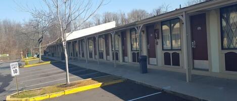 A row of single-story buildings with large windows, a speed limit sign of 10, and a parking lot with marked spaces.