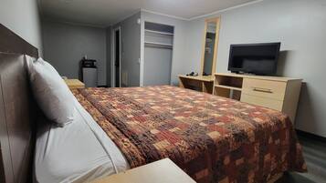 Una habitación de hotel con cama, televisión, armario y escritorio.
