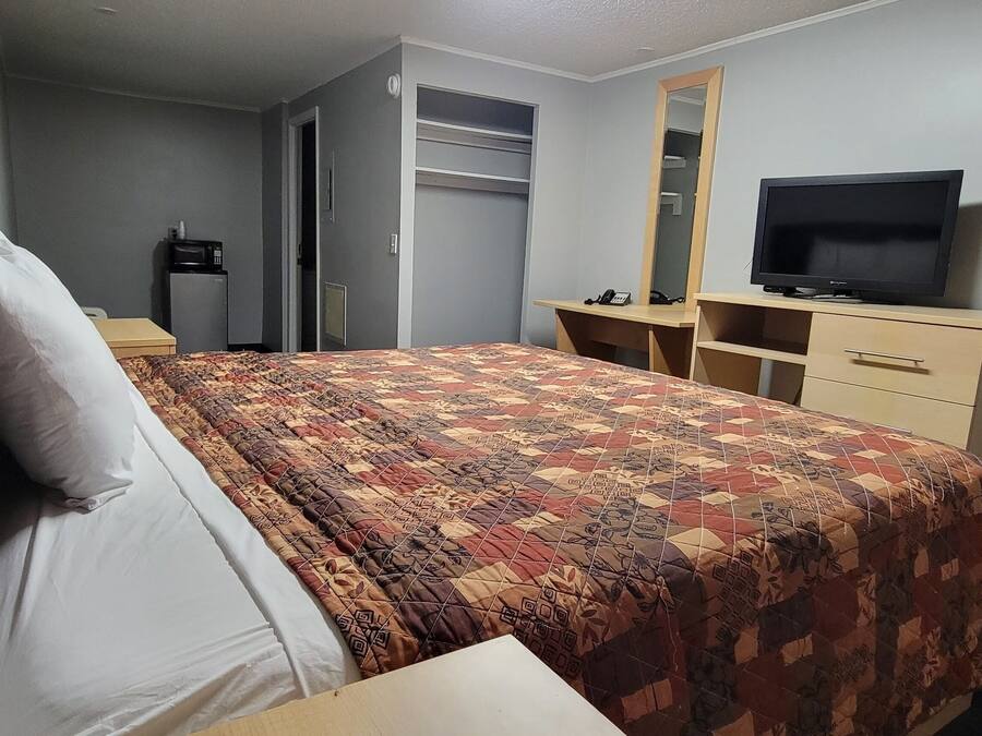 Una habitación de hotel con cama, televisión, armario y escritorio.