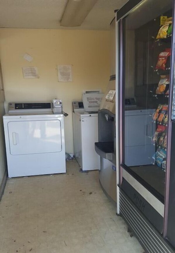 A laundromat with a washing machine, dryer, and a vending machine.