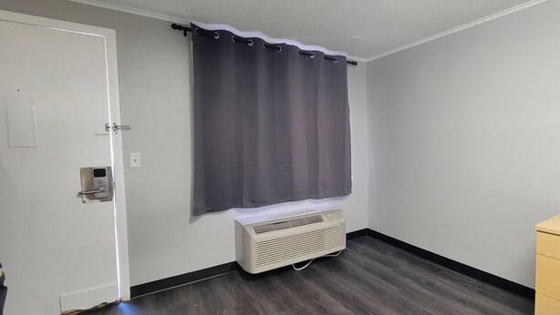 A room with a white door, a gray curtain, a white air conditioning unit, and a wooden cabinet. - Superlodge (New Castle)