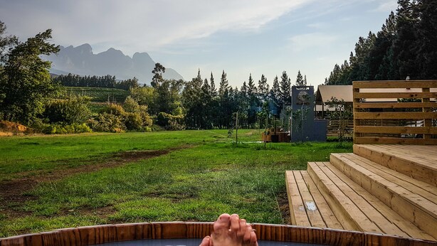A hot tub with a view of a grassy field and mountains in the background.